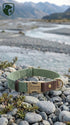 Green dog collar with leather strap on pebbles near a river and mountains