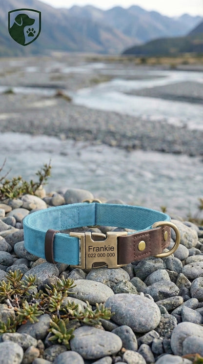 Blue dog collar with a metal tag on pebbles near a mountainous landscape
