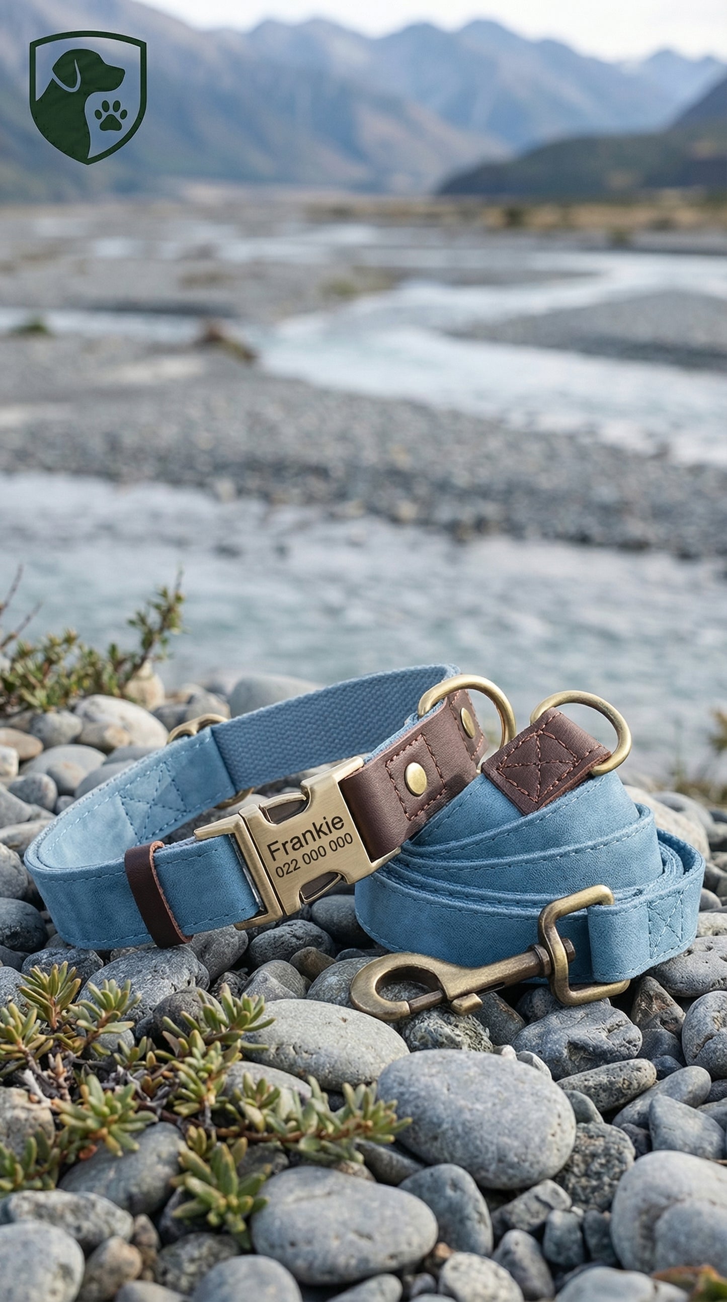 Blue dog collar with brass hardware on pebbles near a mountainous landscape